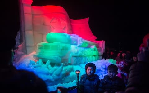 Children pose for a photo before an ice sculpture depicting a Hwasong-15 intercontinental ballistic missile (ICBM) and self-propelled launcher, as people mark the new year at the Pyongyang Ice Sculpture Festival on Kim Il Sung Square in Pyongyang