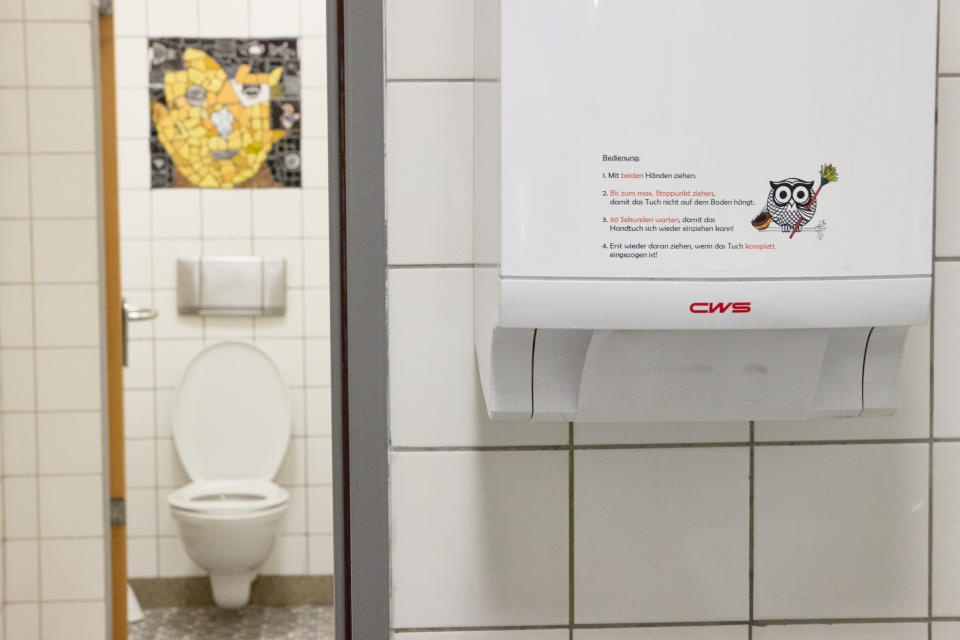 Ein eigens entwickelter Sticker, der die Handhabung erklärt, ist an einem Stoffhandtuchspender in einer Toilette des Gymnasiums Winsen (Bild: dpa)