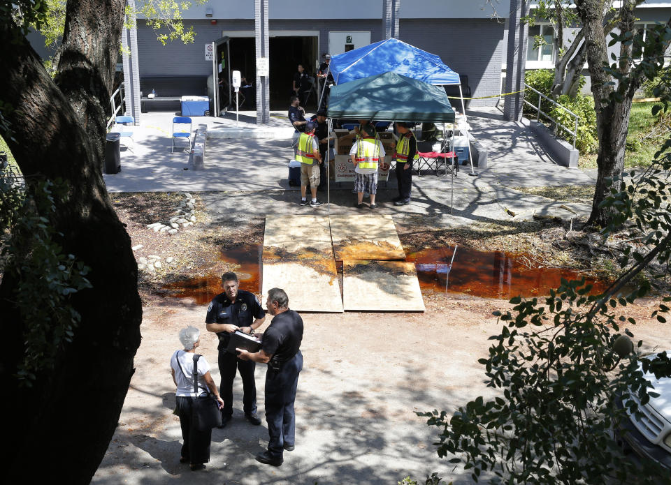 FILE - Police officers talk to an employee at the Rehabilitation Center at Hollywood Hills on Sept. 13, 2017, in Hollywood, Fla. Prosecutors dropped manslaughter charges Thursday, Sept. 22, 2022, against three nurses who had been present when 12 nursing home patients suffered fatal overheating five years ago after a hurricane knocked out power to their facility's air conditioning. (AP Photo/Marta Lavandier, File)