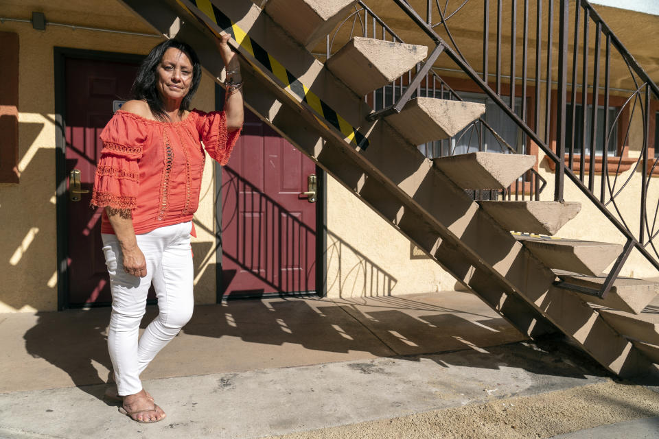 In this Wednesday, June 30, 2021, photo Veronica Perez poses outside at her new home at the Mollie Mason Project Homekey site in Los Angeles. Perez took residence in one of 6,000 new units built statewide over the last year as part of Project Homekey. The California program started in June 2020 is re-purposing vacant hotels, motels and other unused properties as permanent supportive housing for the homeless. (AP Photo/Damian Dovarganes)