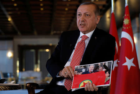 Turkish President Tayyip Erdogan shows a picture as he attends an interview with Reuters at the Presidential Palace in Ankara, Turkey, April 25, 2017. REUTERS/Umit Bektas