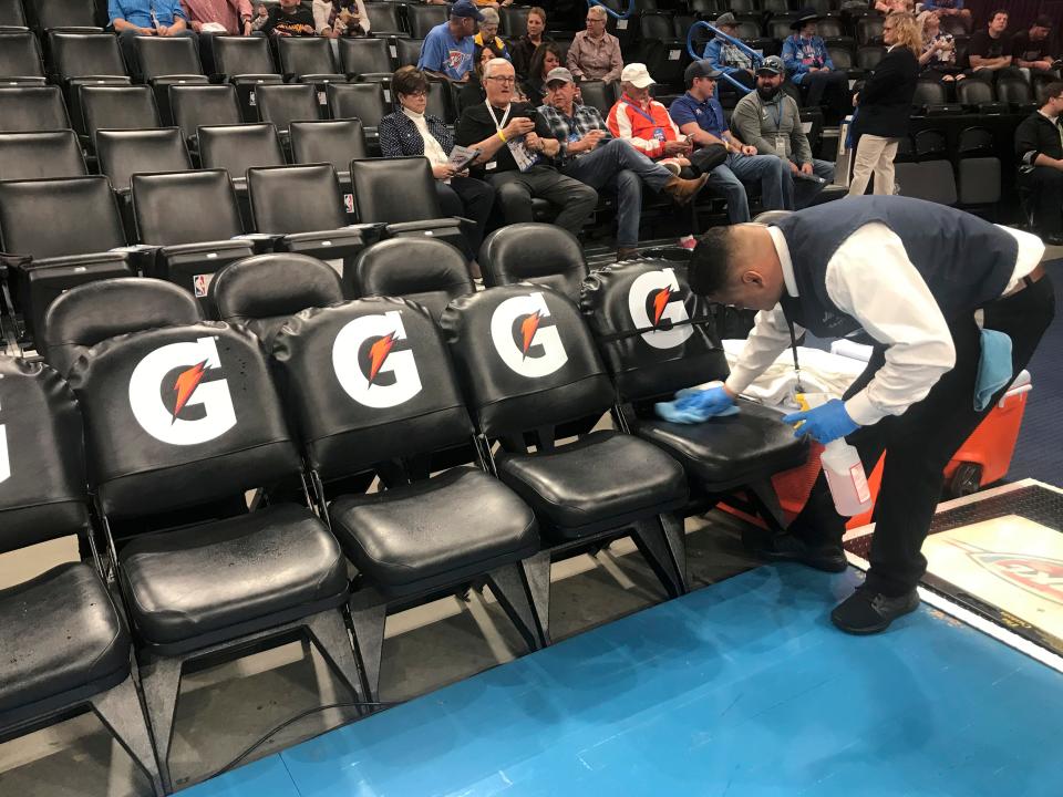A worker cleans the Oklahoma City Thunder bench seats before an NBA basketball game between the Oklahoma City Thunder and the Utah Jazz at Chesapeake Energy Arena in Oklahoma City, Wednesday, March 11, 2020.