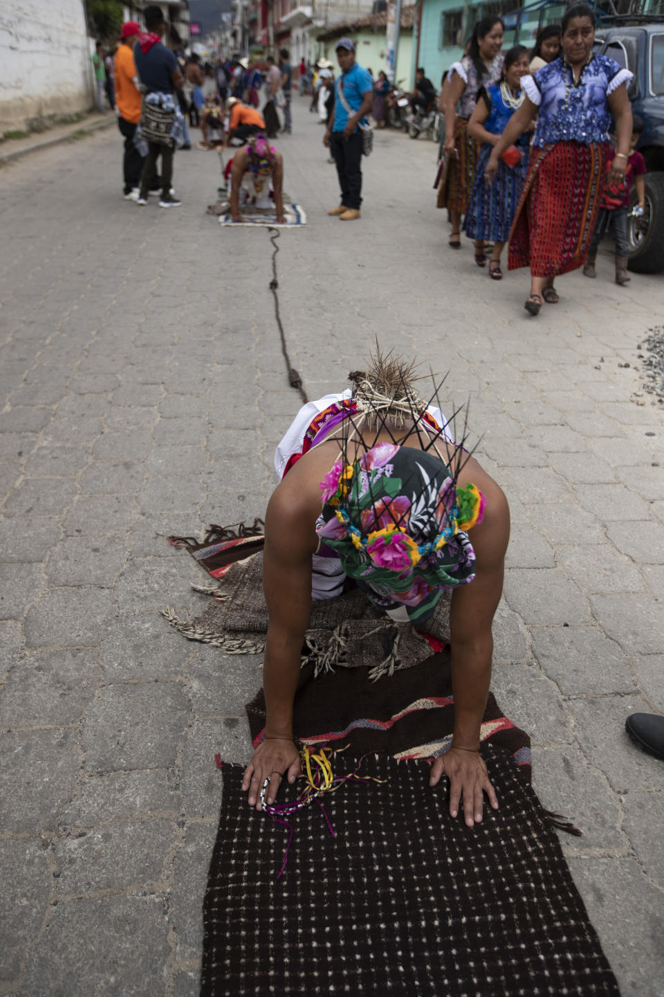 A penitent known as a "gateador" or crawler with a cluster of thorns tied to his back, moves slowly on his knees through the streets in a pilgrimage to Calvary to symbolically purge his sins or give thanks for a promise granted, as part of a Good Friday tradition in San Andres Sajcabaja, Guatemala, Friday, April 2, 2021. Christians in Latin America mark Good Friday this year amid the coronavirus crisis with some religious sites open to limited numbers of faithful but none of the mass pilgrimages usually seen in the Holy Week leading up to Easter. (AP Photo/Moises Castillo)