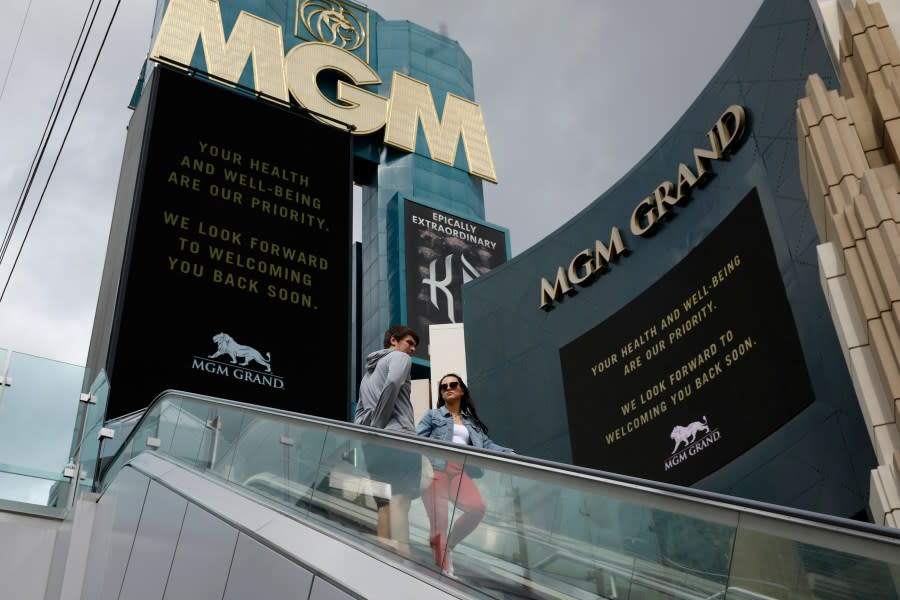 FILE – In this March 16, 2020, file photo, a couple ride the escalator outside The MGM Grand hotel-casino in Las Vegas. (AP Photo/John Locher, File)