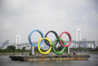 A symbol installed for the Olympic and Paralympic Games Tokyo 2020 on a barge is moved away from its usual spot by tugboats off the Odaiba Marine Park in Tokyo Thursday, Aug. 6, 2020. The five Olympic rings floating on a barge in Tokyo Bay were removed for what is being called “maintenance,” and officials says they will return to greet next year's Games. The Tokyo Olympics have been postponed for a year because of the coronavirus pandemic and are to open on July 23, 2021. The Paralympics follow on Aug. 24. (AP Photo/Hiro Komae)