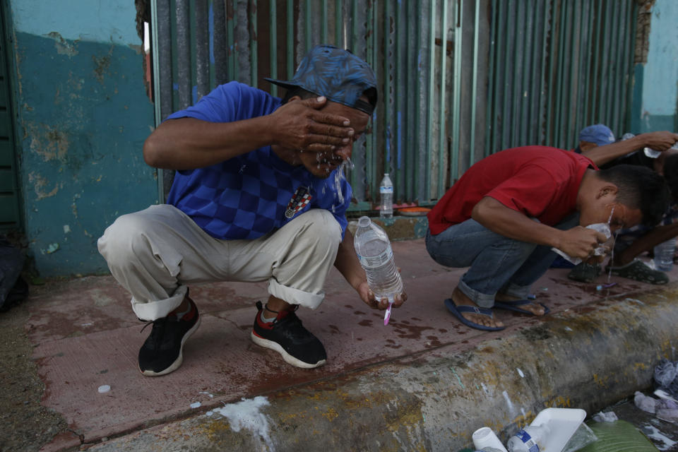 Central American migrants traveling with a caravan to the U.S., use bottled water to wash their faces after waking up, in Huixtla, Mexico, Tuesday, Oct. 23, 2018. The caravan, estimated to include more than 7,000 people, had advanced but still faced more than 1,000 miles, and likely much further, to the end of the journey. (AP Photo/Moises Castillo)