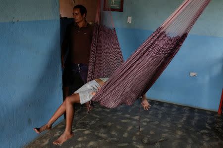 Tulio Medina, father of Eliannys Vivas, who died from diphtheria, stands next to his children as they rest in a hammock at their home in Pariaguan, Venezuela January 26, 2017. REUTERS/Marco Bello