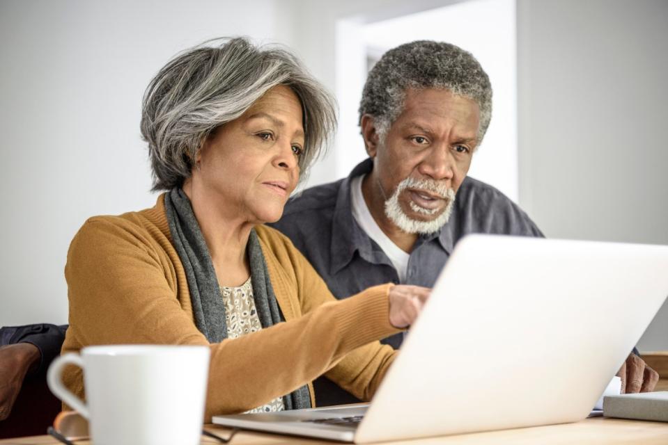 Two people viewing content on a shared laptop while seated at a table.