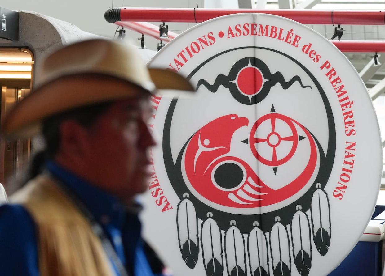 An attendee walks past a banner at the Assembly of First Nations annual general assembly in Montreal on Tuesday.  (The Canadian Press/Christinne Muschi - image credit)