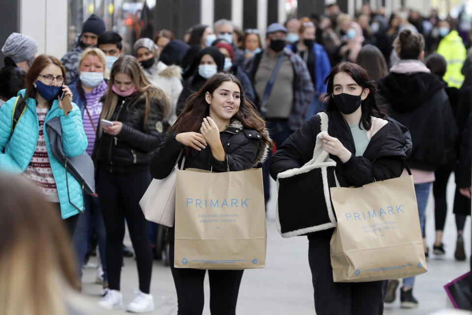 FILE - In this Monday, April 12, 2021 file photo, people carry shopping bags as others queue to enter a store on Oxford Street in London, as the government takes the next step on its lockdown-lifting road map. Thanks to an efficient vaccine roll out program and high uptake rates, Britain is finally saying goodbye to months of tough lockdown restrictions. From Monday May 17, 2021, all restaurants and bars can fully reopen, as can hotels, cinemas, theatres and museums, and for the first time since March 2020, Britons can hug friends and family and meet up inside other people’s houses. (AP Photo/Kirsty Wigglesworth, File)