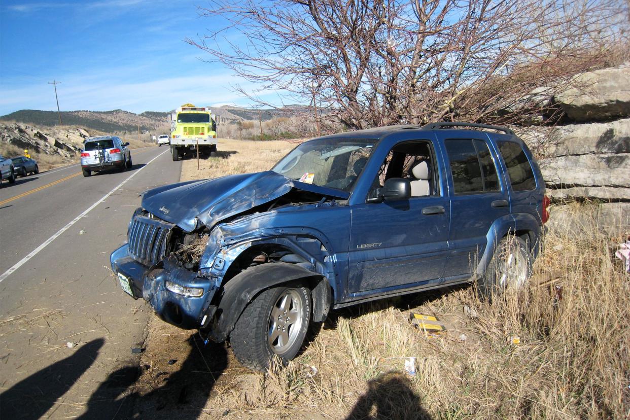 Crashed Blue Jeep on road.