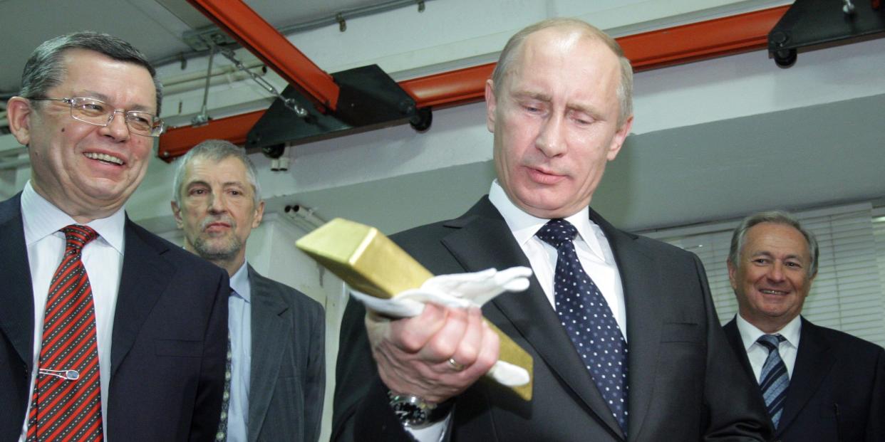 Vladimir Putin holds a gold bar while visiting the Central Depository of the Bank of Russia when he was prime minister on January 24, 2011.