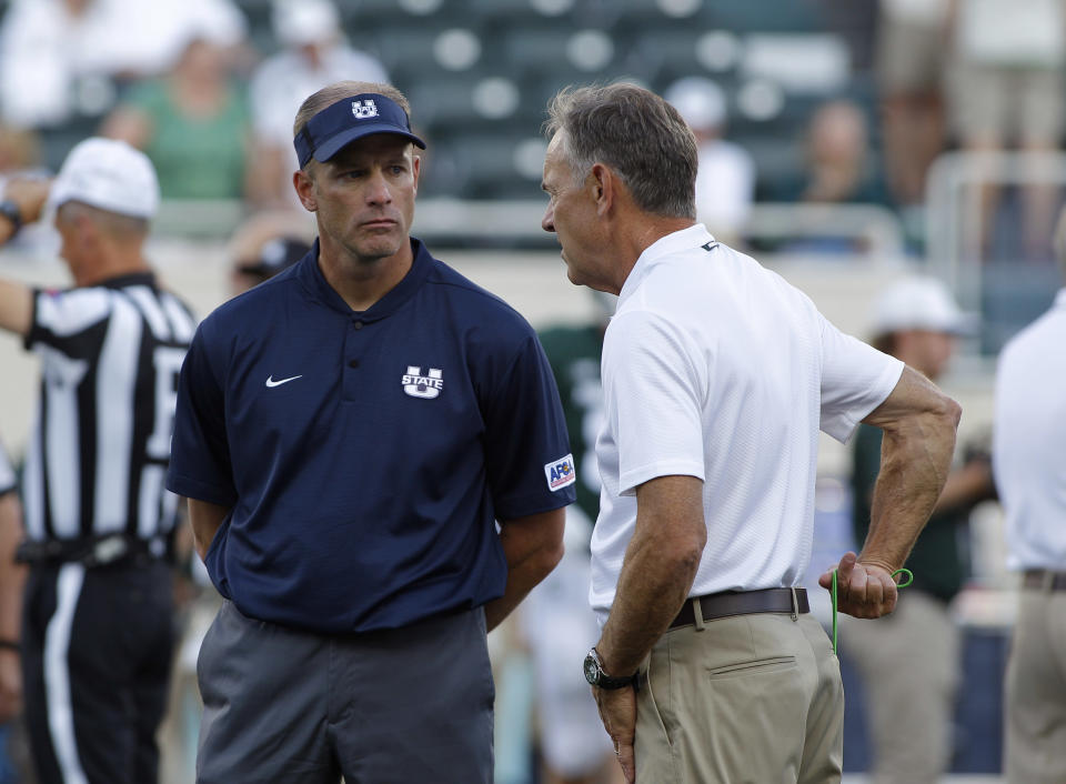 Utah State coach Matt Wells, left, and Michigan State coach Mark Dantonio talk before an NCAA college football game, Friday, Aug. 31, 2018, in East Lansing, Mich. (AP Photo/Al Goldis)