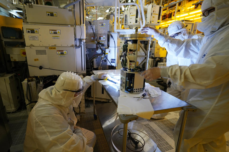 FILE - Technicians inspect a piece of equipment during a tour of the Micron Technology automotive chip manufacturing plant Feb. 11, 2022, in Manassas, Va. A bill to boost semiconductor production in the United States is making its way through the Senate is a top priority of the Biden administration. It would add about $79 billion to the deficit over 10 years, mostly as a result of new grants and tax breaks that would subsidize the cost that computer chip manufacturers incur when building or expanding chip plants in the U.S. (AP Photo/Steve Helber, File)