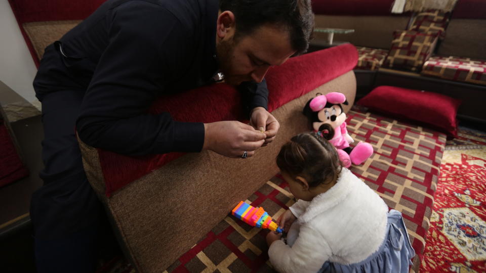 In this Sunday, Feb. 23, 2020 photo, Abdullah Mohammed plays with his daughter, three-year-old Salwa inside a house he recently fled to, near the Syrian-Turkish border, in Sarmada, Syria. Mohammed would do anything for his daughter, even if that means forcing himself to laugh with her at the sound of exploding bombs, to help her overcome her fear. Mohammed and Salwa became an overnight celebrity after a video they shot spread on social media, widely shared as a reminder of the horrors faced by children in Syria. (AP Photo/Ghaith Alsayed)