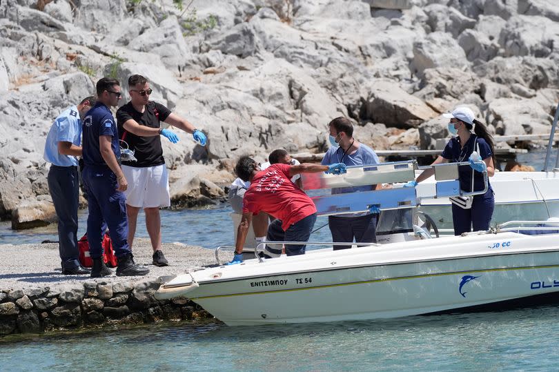 Emergency services lifting an empty stretcher off a boat at Agia Marina in Symi, Greece