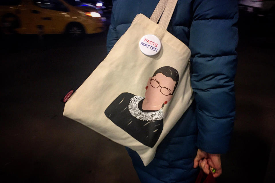 Image: A woman carries an RGB tote bag with a pin that reads, 