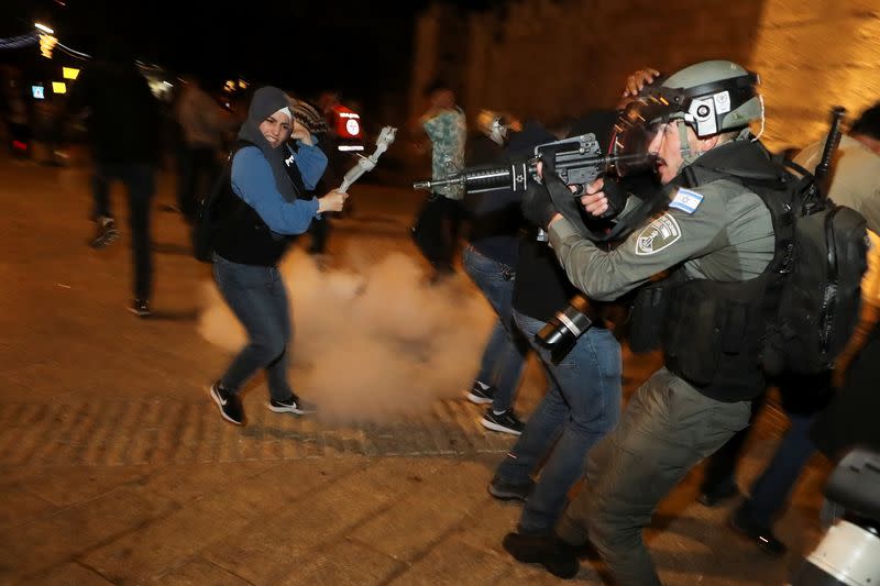 Israeli police officer stands in position as a stun grenade explodes by the gate to Jerusalem's Old City