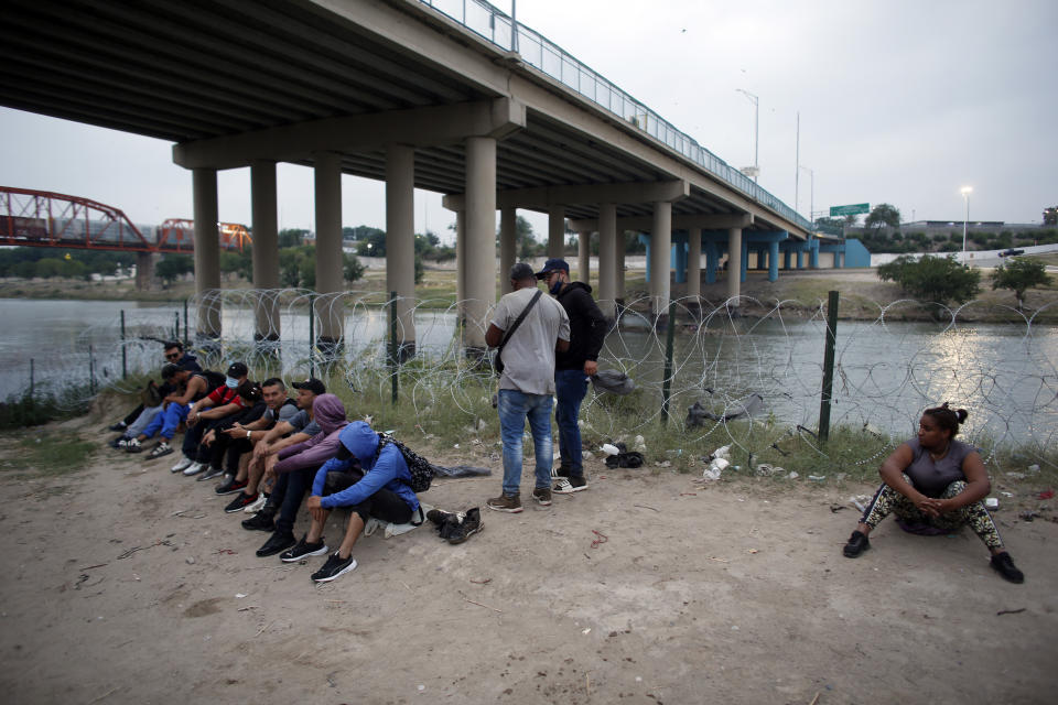 Ana Rita Pinales, 28, from the Dominican Republic, right, and other migrants who had crossed the Rio Grande river into the U.S., are under custody of National Guard members as they await the arrival of U.S. Border Patrol agents in Eagle Pass, Texas, Friday, May 20, 2022. The Eagle Pass area has become increasingly a popular crossing corridor for migrants, especially those from outside Mexico and Central America, under Title 42 authority, which expels migrants without a chance to seek asylum on grounds of preventing the spread of COVID-19. A judge was expected to rule on a bid by Louisiana and 23 other states to keep Title 42 in effect before the Biden administration was to end it Monday. (AP Photo/Dario Lopez-Mills)