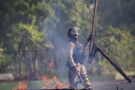 A Haitian National Police (PNH) clears a barricade during clashes at a demonstration to demand the resignation of Haitian president Jovenel Moise, in the streets of Petion Ville, Port-au-Prince