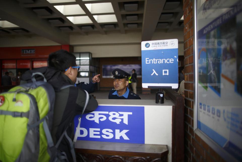 A passenger makes enquires with a Nepalese police officer after a Turkish Airlines plane overshot a runway at Tribhuvan International Airport in Kathmandu