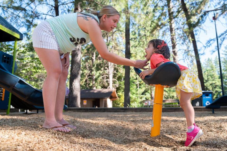 Madison Ridenour, left, asks her daughter, Ava King, 2, not to lick pieces of equipment at Paradise Rotary Playground in Paradise on Friday. Ridenour said she was trying to remain calm and let her daughter spend time outside in case the Park Fire gets any closer.