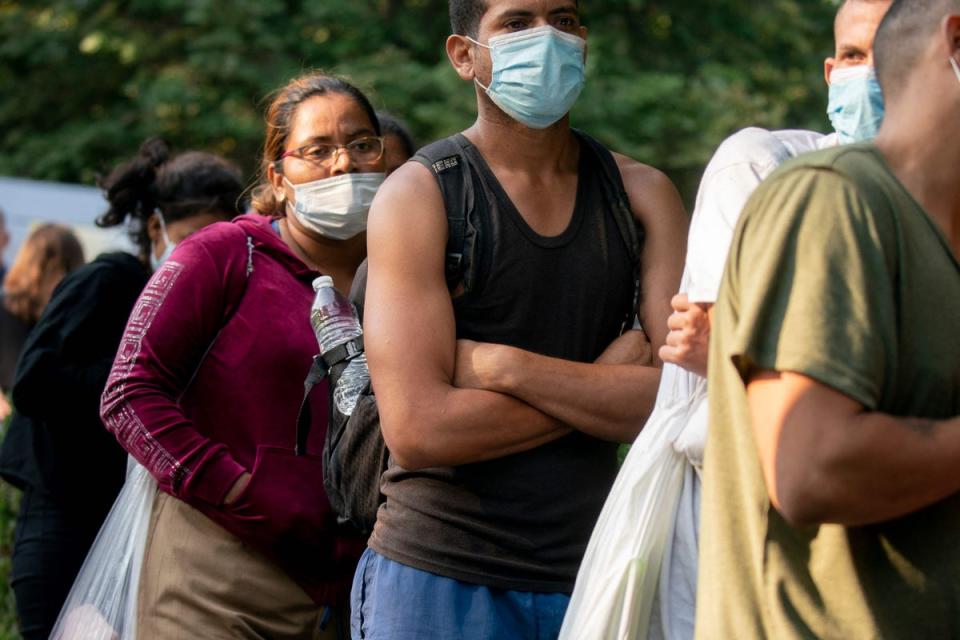 A group of mostly Venezuelan migrants dropped off outside Vice President Kamala Harris’s residence in Washington DC wait for transport to a local church on 15 September. (AFP via Getty Images)