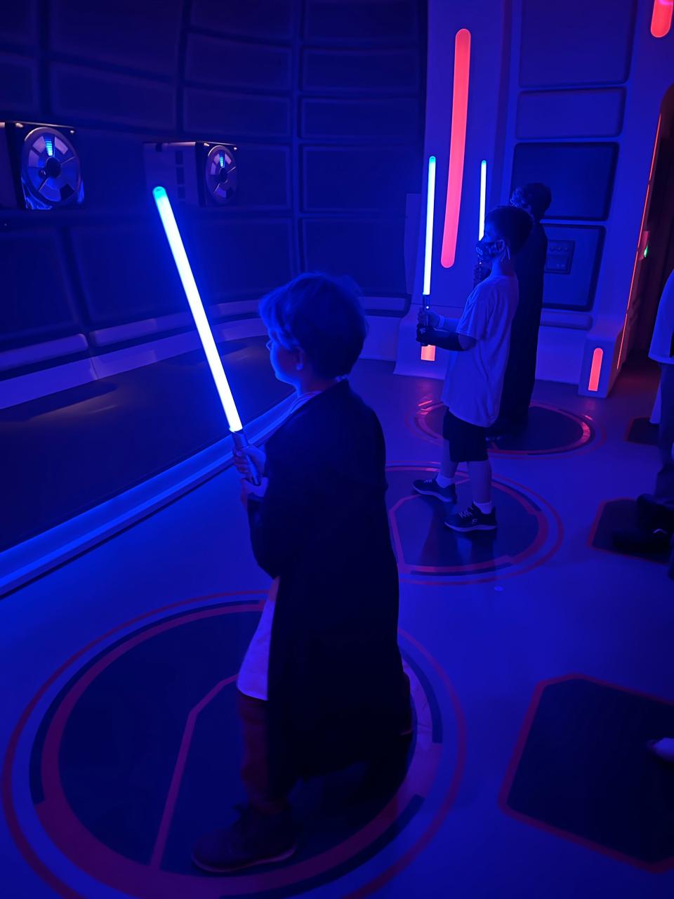 My son with a lightsaber at the training in a blue-lit room on the starcruiser