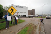 FILE - In this May 20, 2020, file photo, residents cheer and hold thank you signs to greet employees of a Smithfield pork processing plant as they begin their shift in Sioux Falls, S.D. Smithfield called many employees back to work after it closed the plant for more than three weeks because of a coronavirus outbreak that infected over 800 employees. (AP Photo/Stephen Groves, File)