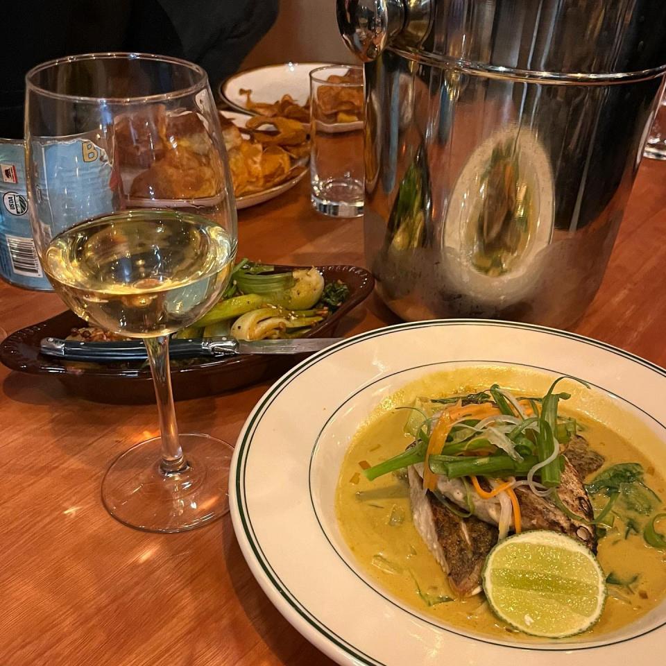 Pan seared barramundi with laksa curry sauce, sautéed seasonal greens, pickled carrot, and daikon at Harvey's restaurant in Louisville.