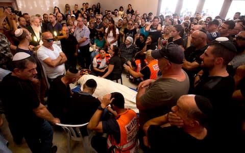 Relatives and friends gather around the body of Yotam Ovadia during his funeral in Jerusalem - Credit: AP Photo/Sebastian Scheiner