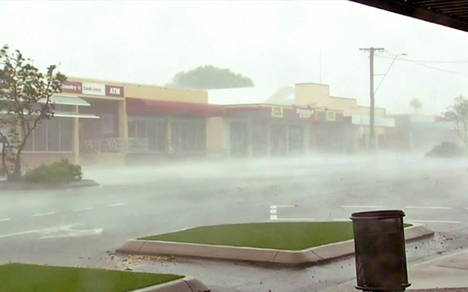 Wind gusts outside shops in Bowen, eastern Australia - Credit: AuBC via AP