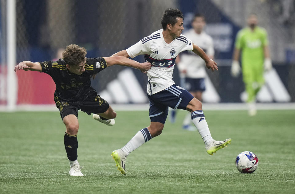 Los Angeles FC's Nathan Ordaz, left, grabs the jersey of Vancouver Whitecaps' Andres Cubas as they vie for the ball during the second half in Game 2 of a first-round MLS playoff soccer match in Vancouver, British Columbia, Sunday, Nov. 5, 2023. (Darryl Dyck/The Canadian Press via AP)