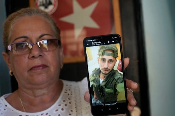 Marilin Vinent holds up a photo of her son Dannys Castillo dressed in military fatigues in an Aug. 22 message from her son that reads in Spanish "I'm already entangled" during an interview at her home in Havana, Cuba, Friday, Sept. 8, 2023. Vinent said that her son and other Cubans traveled at the end of July to Russia after being promised work in a construction job, but that he was one of the Cubans recruited to fight for Russia in Ukraine. <span class="copyright">Ramon Espinosa—AP</span>
