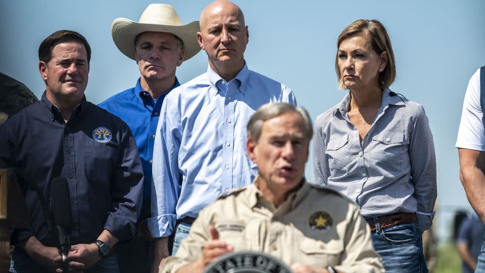 Iowa Gov. Kim Reynolds, right, stands with a group of governors behind Texas Gov. Greg Abbott during a news conference in the border city of Mission, Texas, in October 2021. - Sergio Flores/Bloomberg/Getty Images