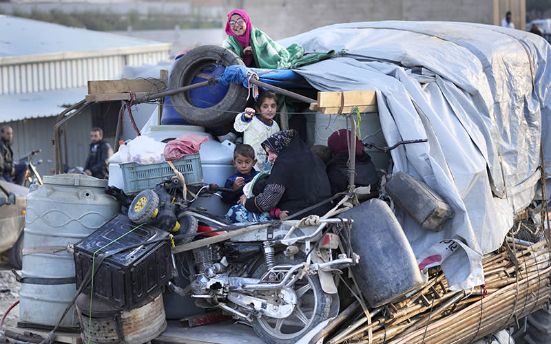 Syrian refugees sit in the back of a truck next to their belongings