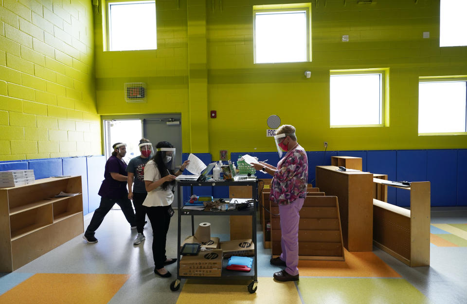 Teachers at Menchaca Early Childhood Center pass out tablets to students, Thursday, Aug. 13, 2020, in San Antonio. Southside will being the year with remote teaching and has added hotspots to the school district to help students without access to the internet. (AP Photo/Eric Gay)