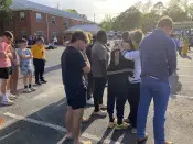 A woman embraces Dadeville High School football player Antojuan Woody at a prayer vigil on Sunday, April 16, 2023, outside First Baptist Church in Dadeville, Ala. Alabama law enforcement officers were imploring people to come forward with information about a shooting that killed multiple people and injured over two dozen others during a teenager's birthday party on Saturday, April 15. (AP Photo/Jeff Amy)