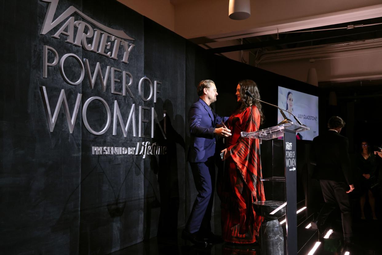 Honoree Lily Gladstone, right, accepts an award from her "Killers of the Flower Moon" co-star Leonardo DiCaprio onstage during Variety Power of Women Los Angeles presented by Lifetime at Mother Wolf on November 16, 2023 in Los Angeles, California.