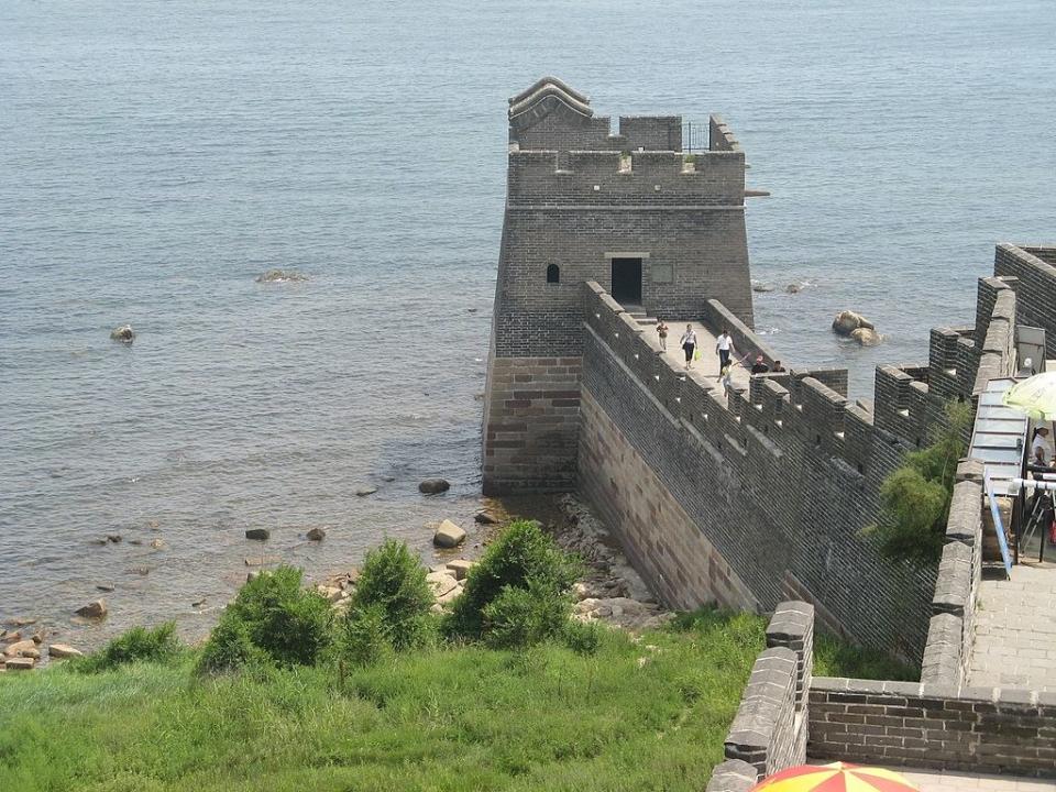 A gray brick and stone edifice emerging from the water at the shore