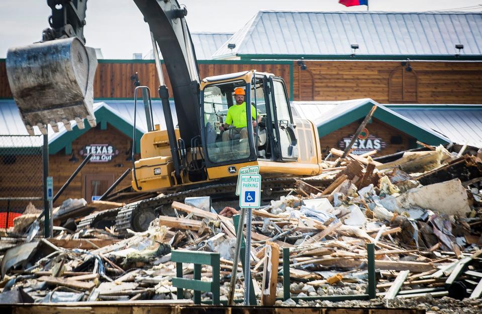 The newly constructed Texas Roadhouse restaurant on McGalliard Road can be seen behind demolition of the old one Tuesday, May 26, 2020.