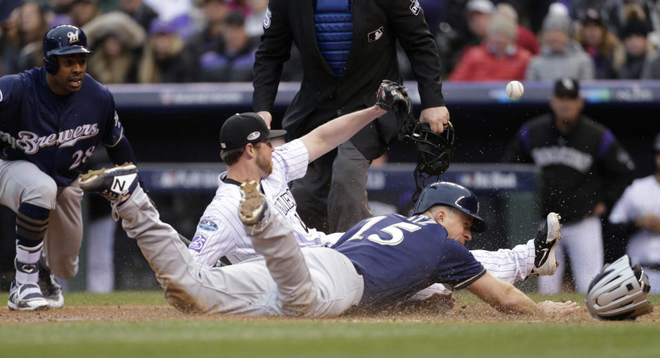 Milwaukee Brewers' Erik Kratz, front, slides safely into home plate to score on a wild pitch by Colorado Rockies relief pitcher Scott Oberg as he tries to field the throw from catcher Tony Wolters in the sixth inning of Game 3 of a baseball National League Division Series Sunday, Oct. 7, 2018, in Denver. (AP Photo/Joe Mahoney)