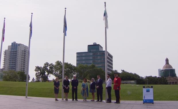 First responders, MLAs and Alberta Lieutenant Governor Salma Lakhani take part in a flag raising ceremony outside the Federal building in Edmonton on Sunday to mark the first annual United Nations World Drowning Prevention Day. (Gabrielle Brown/CBC - image credit)