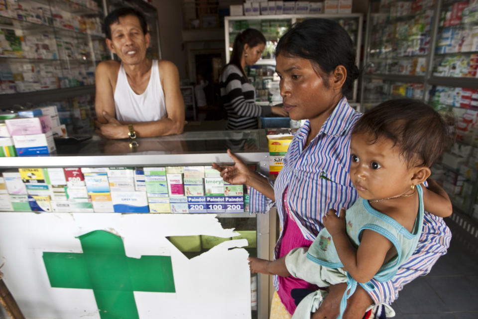 FILE - In this Aug. 26, 2009 file photo, a merchant speaks with a woman holding her sick child at a pharmacy in Pailin, Cambodia. More than a third of the malaria-fighting drugs tested over the past decade in Southeast Asia and sub-Saharan Africa were either fake or bad quality, seriously undermining efforts to combat the disease, a study said Tuesday, May 22, 2012. (AP Photo/David Longstreath, File)