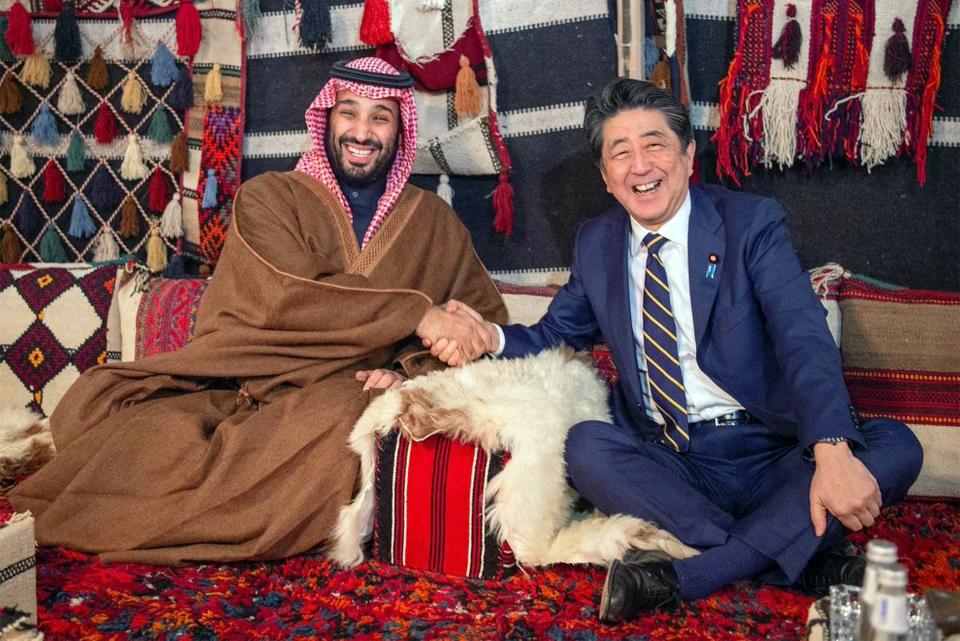 FILE - In this Sunday, Jan. 12, 2020 file photo, released by Saudi Press Agency, Japan's Prime Minister Shinzo Abe, right, wearing a traditional Saudi robe, shakes hands with Saudi Crown Prince Mohammed bin Salman inside a tent in the northwestern desert region of Al-Ula, north of Medina, Saudi Arabia. A flurry of diplomatic visits and meetings crisscrossing the Persian Gulf are driving urgent efforts to defuse the possibility of all-out war after the U.S. killed Iran's top military commander. Global leaders and top diplomats are repeating in recent days the mantra of “de-escalation” and “dialogue,” yet none have publicly laid out a path to achieving either. (Saudi Press Agency via AP)