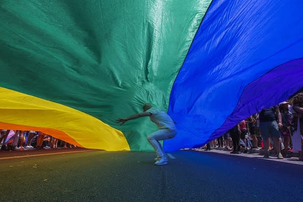 A man runs under a rainbow flag as it is carried in the 48th annual LA Pride Parade on June 10, 2018, in the Hollywood section of Los Angeles and West Hollywood, California. The annual gay rights event returns to its customary format of celebration following a one-time switch to the Resist March protest against Trump administration policies. LA Pride began on June 28, 1970, exactly one year after the historic Stonewall Rebellion in New York City. (Photo by David McNew/Getty Images)