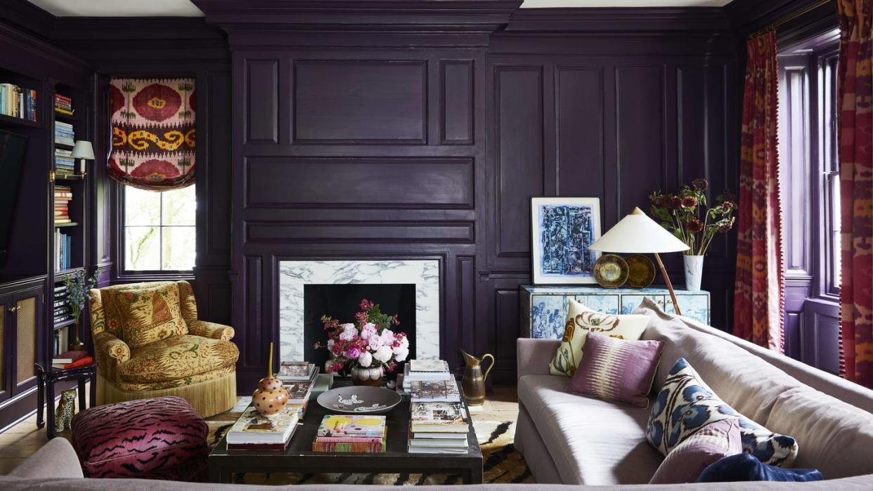 a custom mohair sectional in a library surrounds a table and the walls are a dark eggplant hue