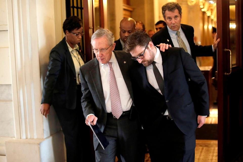 Then-Senate Majority Leader Harry Reid (C) pulls communications director Adam Jentleson (R) close while walking to a government shutdown-related press event on the steps of the US Capitol on October 9, 2013 in Washington, DC.