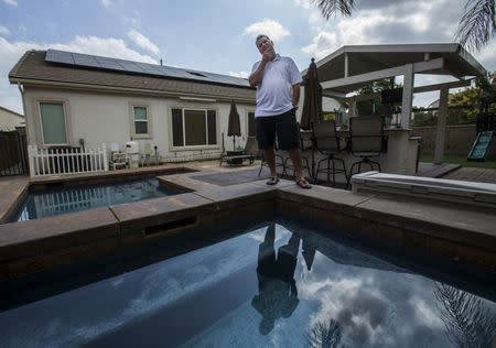 Home owner Steven Lista stands in his back yard under the solar panels he financed using a government sponsored system in Eastvale, California September 4, 2015. REUTERS/Mike Blake