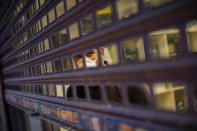 A man, wearing a face mask due the coronavirus outbreak, looks from behind a gate in downtown Madrid, Spain, Tuesday, March 24, 2020. More than 1.5 billion around the world have been told to stay in their homes. For most people, the new coronavirus causes only mild or moderate symptoms. For some it can cause a more serious illness. (AP Photo/Bernat Armangue)